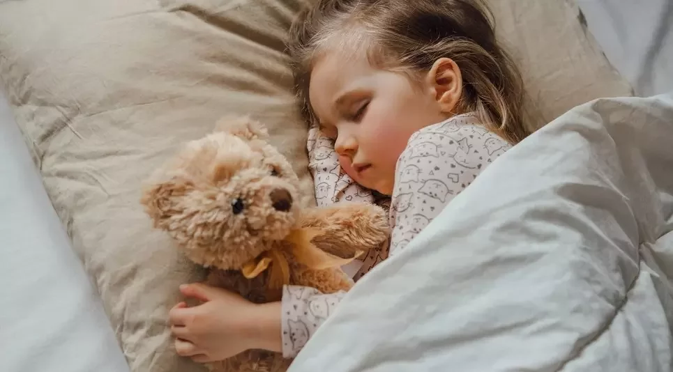 Jeune enfant qui dort dans son lit avec une beluge
